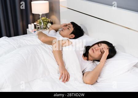 Kranke Paar Kopfschmerzen und Leiden von Viruserkrankungen und Fieber auf dem Bett zu Hause Stockfoto