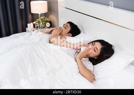 Kranke Paar niesen und leiden an Viruserkrankungen und Fieber auf dem Bett zu Hause Stockfoto
