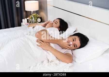Kranke Paar niesen und leiden an Viruserkrankungen und Fieber auf dem Bett zu Hause Stockfoto