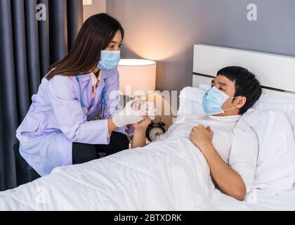 Arzt im Gespräch und Beratung mit kranken Mann auf dem Bett, müssen die Menschen tragen medizinische Maske Schutz vor Coronavirus (Covid-19) Pandemie Stockfoto