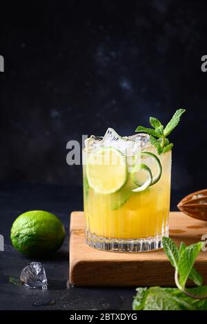 Mai Tai Cocktail. Rum mit tropischen Früchten, Eiswürfel und Limettengarnitur Minze auf Schwarz. Vertikales Format. Nahaufnahme. Stockfoto