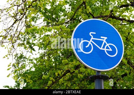 Nachhaltiger Verkehr. Blaues Straßenschild oder Signal der Fahrradweg mit grünen Bäumen und Natur Hintergrund Stockfoto