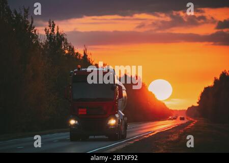 Roter Stapler Oder Traktoreinheit, Prime Mover, Fahreinheit In Bewegung Auf Der Straße, Freeway. Asphalt Motorway Highway Vor Dem Hintergrund Von Big Sunset Sun Busin Stockfoto