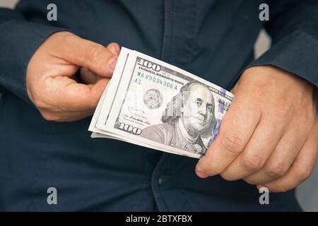 Ein Mann betrachtet Dollarscheine auf einem dunklen Hintergrund, Konzept der finanziellen Unabhängigkeit Stockfoto
