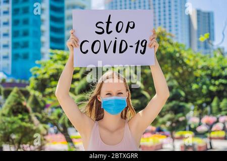 Frau in medizinischer Maske verhindert Coronavirus-Krankheit hält ein Poster Stop covid 19 handgeschriebenen Text - Schriftzug isoliert auf weiß. Coronovirus COVID 19 Stockfoto