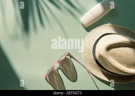 Sonnenhut, Brille und spf Creme oder Lotion unbranded Paket auf hellblauem Hintergrund mit Palmblatt Schatten, Draufsicht, flach legen. Sommerurlaub CO Stockfoto