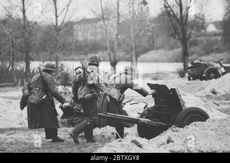 Re-enactors gekleidet als deutsche Soldaten im Zweiten Weltkrieg AreRoll Out Cannon in der Schussposition Stockfoto