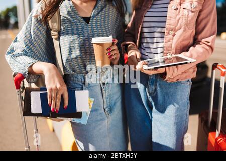 Nahaufnahme Mädchen mit Koffern, die Kaffee zu gehen, Pässe mit Tickets und die Tablette in den Händen am Flughafen Stockfoto