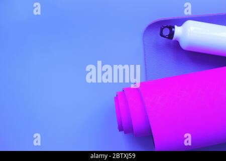 Leuchtend lila Yogamatte und eine Flasche Wasser. Stockfoto