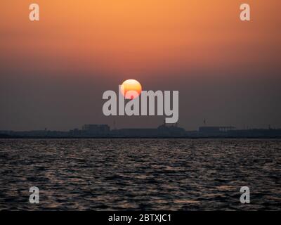 Wunderschöner Sonnenuntergang und Meerblick über der stadt izmir. Die Sonne ist fast bis zum Meer hinunter gefallen. Stockfoto