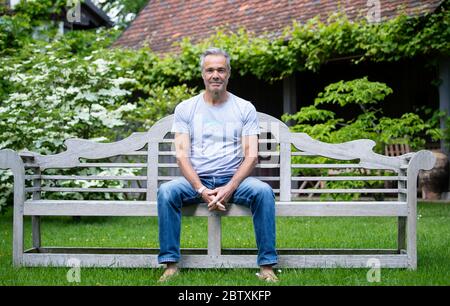 Utting, Deutschland. Mai 2020. EXKLUSIV - Hannes Jaenicke, Schauspieler, sitzt während eines Fotoshootings in seinem Garten. Jaenicke rät vom Lachsessen ab. Für eine ZDF-Dokumentation hat sich der Schauspieler mit dem Fisch beschäftigt. Der Film "Hannes Jaenicke: In Aktion für den Lachs" wird am 16. Juni um 10.15 Uhr im ZDF ausgestrahlt. Kredit: Sven Hoppe/dpa/Alamy Live News Stockfoto