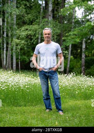 Utting, Deutschland. Mai 2020. EXKLUSIV - Hannes Jaenicke, Schauspieler, steht während einer Fotosession in seinem Garten. Jaenicke rät vom Lachsessen ab. Für eine ZDF-Dokumentation hat sich der Schauspieler mit dem Fisch beschäftigt. Der Film "Hannes Jaenicke: In Aktion für den Lachs" wird am 16. Juni um 10.15 Uhr im ZDF ausgestrahlt. Kredit: Sven Hoppe/dpa/Alamy Live News Stockfoto