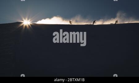 Skifahrer genießen einen frühen Morgen auf den Pisten der österreichischen Alpen mit schöner Sonneneinstrahlung Stockfoto