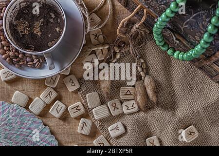 Isoterisches Konzept der Weissagung und Vorhersage. Tarot-Karten, Runen, Kaffeesatz in einer Tasse, Rosenkranz auf einem Tisch vor dem Hintergrund einer alten Brust Stockfoto