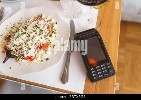 Kontaktloser Kartenleser und Teller Salat auf dem Tisch im Restaurant Stockfoto