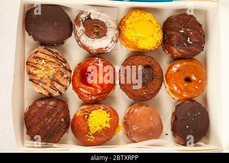 Verschiedene Gourmet-Donuts mit Füllung und leckeren Belägen frisch gebacken in einer Box für die Lieferung herausnehmen Stockfoto