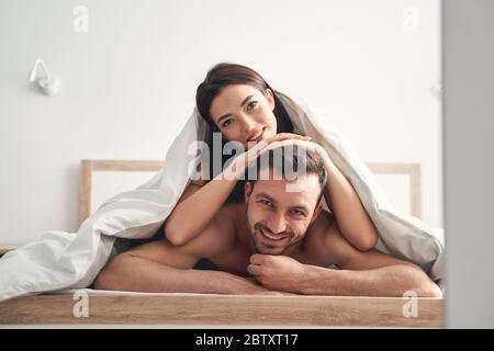 Junge Frau, die auf dem Rücken ihres Ehemannes liegt Stockfoto
