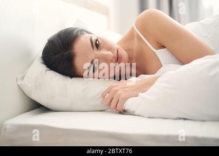 Fröhlose Dame unter der Decke in einem Schlafzimmer Stockfoto