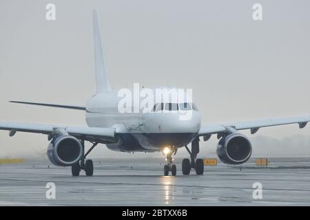 Vorderansicht der Passagiere Schmalkörper-Flugzeug Fahrten nach der Landung in der Dämmerung, Rollen auf der Start-und Landebahn, bewölktes Wetter. Luftfahrt, Transport Stockfoto