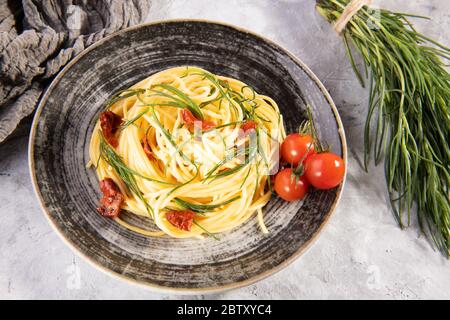 Spaghetti mit agretti, einem Frühlingsgemüse aus Italien, sonnengetrockneten Tomaten und Zutaten, italienisches Essen Stockfoto