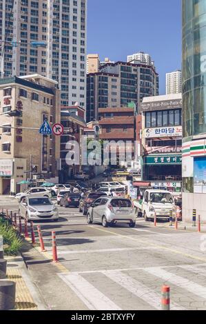 Busan, Südkorea, 14. September 2019: Schmale koreanische Straße voller Autos und Gebäude in der Nähe des Songdo-Strandes an sonnigen Tagen Stockfoto