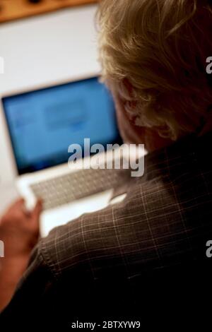 Über Schulter Rückansicht von weißhaarigen Rentner mit Laptop-Computer zu Hause. Stockfoto