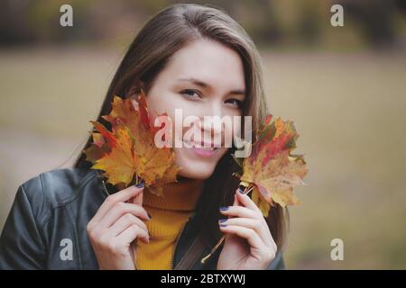 Junge Frau mit Herbstlaub in den Händen Porträt Stockfoto