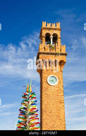 Spitze der Murano-Uhrturm Torre dell'Orologio und bunten weihnachtsbaum aus Murano-Glas auf Campo Santo Stefano Platz, Murano-Inseln, Region Venetien, Norditalien, Vertikale Ansicht Stockfoto