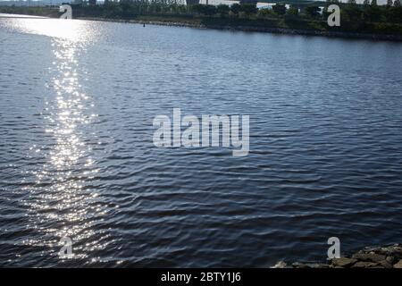 Die Sonnenstrahlen auf dem ruhigen Fluss Stockfoto