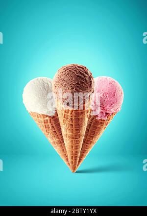 Eis aus Schokolade, Erdbeere und Vanille mit Kegel auf blauem Hintergrund. Drei verschiedene Geschmacksrichtungen Stockfoto