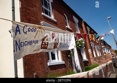 Duncombe Street in Wollaston, wo der Künstler Luke Perry mit Botschaften der Unterstützung für Nachbarn und Schlüsselarbeiter aufgehängt hat, um einen 500 Meter langen Korridor von Farbe durch das Dorf West Midlands zu schaffen. Herr Perry bat die Anwohner und Ladenbesitzer, Entwürfe und Botschaften einzureichen, die er dann mit Hilfe von Freiwilligen handbemalt und auf die Amme genäht hatte. Stockfoto