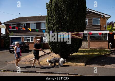 Duncombe Street in Wollaston, wo der Künstler Luke Perry mit Botschaften der Unterstützung für Nachbarn und Schlüsselarbeiter aufgehängt hat, um einen 500 Meter langen Korridor von Farbe durch das Dorf West Midlands zu schaffen. Herr Perry bat die Anwohner und Ladenbesitzer, Entwürfe und Botschaften einzureichen, die er dann mit Hilfe von Freiwilligen handbemalt und auf die Amme genäht hatte. Stockfoto