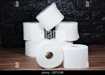 Viele Rollen weißes Einweg-Toilettenpapier im Badezimmer auf einem braunen Holztisch Stockfoto