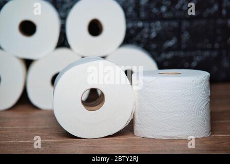 Rollen von Einweg-Toilettenpapier mit Karton auf einem braunen Holztisch Stockfoto