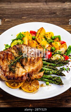 Gegrilltes Steak mit Spargel und gegrilltem Gemüse auf Holztisch Stockfoto