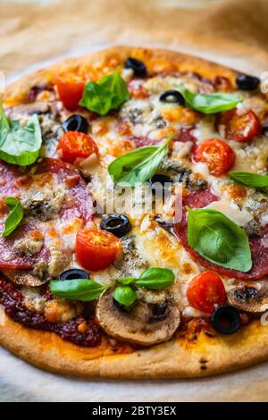 Pepperoni Pizza mit Salami, Oliven, Kirschtomaten und Basilikum Stockfoto