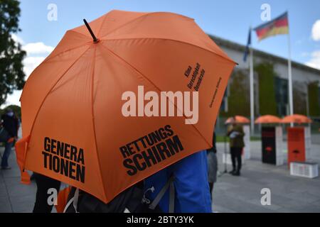 Berlin, Deutschland. Mai 2020. Ein Demonstrator hält einen Schirm vor dem Kanzleramt als Auftakt zur Kampagne "Generationenschirm" der Generationenstiftung. Eines der Ziele der Kampagne ist es, die Corona-Wirtschaftshilfe mit sozialen und ökologischen Bedingungen zu verknüpfen. Quelle: Sven Braun/dpa/Alamy Live News Stockfoto