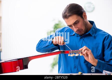 Junger Mann Reparatur der Gitarre Stockfoto