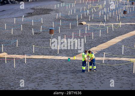 Playa de La Arena, Santiago del Teide, Teneriffa, Kanarische Inseln, Spanien. Mai 2020. Die Arbeiter bereiten den Strand mit abgesperrten Bereichen vor, um die soziale Distanz, zwei Meter voneinander entfernt, und den kontrollierten Zugang für die Öffentlichkeit während der zweiten Phase der Deeskalation des Covid 19, Coronavirus Notstand, der voraussichtlich bis zum 7. Juni dauern wird. Stockfoto