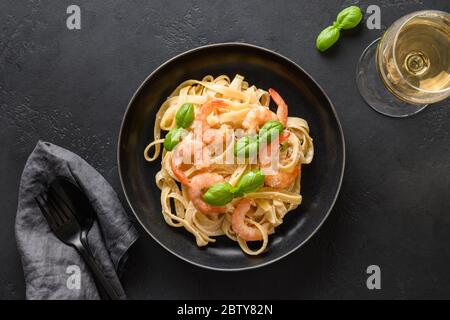 Italienische Fettuccine mit Garnelen, Meeresfrüchte serviert Weinglas auf schwarzem Tisch. Blick von oben. Stockfoto