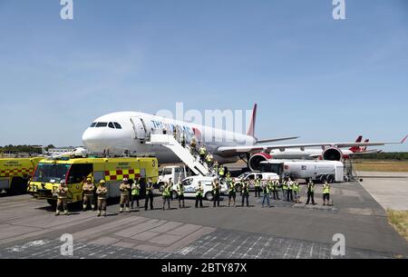 Die Besatzung eines Fluges der European Aviation Group, der nach China abreist, um PSA abzuholen, steht vor ihrem Flugzeug am internationalen Flughafen Bournemouth, zusammen mit Mitarbeitern und Feuerwehrleuten vom Flughafen Bournemouth, Während sie sich dem Applaus anschließen, um lokale Helden während des landesweiten Clap for Carers am Donnerstag zu begrüßen, um NHS-Arbeiter und Betreuer zu erkennen und zu unterstützen, die gegen die Coronavirus-Pandemie kämpfen. Stockfoto