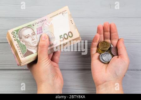 Geld der Ukraine. Stapel ukrainischer Griwna-Banknoten in den Händen auf dem hölzernen Tisch. Griwna 500 und Münzen Stockfoto