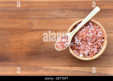 Himalaya-Salz auf einen Löffel und in eine Schüssel auf Holz Hintergrund gelegt Stockfoto