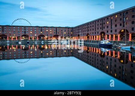 Das Rad von Liverpool hinter dem Albert Dock am Ufer des Flusses Mersey, UNESCO-Weltkulturerbe, in der Abenddämmerung (blaue Stunde) Stockfoto