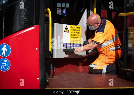Busmitarbeiter installieren Aufkleber auf einem Bus in der Twickenham Busgarage, um Kunden daran zu erinnern, dass die Fahrpreise auf der Strecke während der COVID-19 pandemi in Betrieb sind Stockfoto