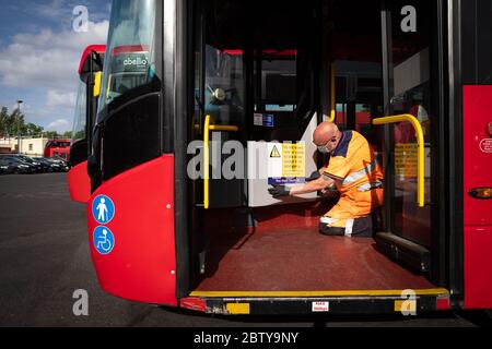 Busmitarbeiter installieren Aufkleber auf einem Bus in der Twickenham Busgarage, um Kunden daran zu erinnern, dass die Fahrpreise auf der Strecke während der COVID-19 pandemi in Betrieb sind Stockfoto