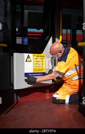 Busmitarbeiter installieren Aufkleber auf einem Bus in der Twickenham Busgarage, um Kunden daran zu erinnern, dass die Fahrpreise auf der Strecke während der COVID-19 pandemi in Betrieb sind Stockfoto