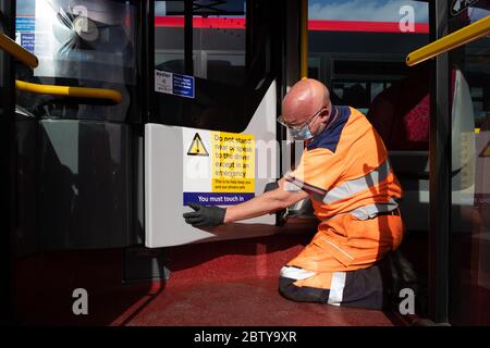 Busmitarbeiter installieren Aufkleber auf einem Bus in der Twickenham Busgarage, um Kunden daran zu erinnern, dass die Fahrpreise auf der Strecke während der COVID-19 pandemi in Betrieb sind Stockfoto