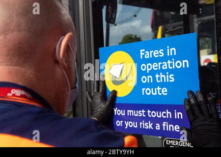 Busmitarbeiter installieren Aufkleber auf einem Bus in der Twickenham Busgarage, um Kunden daran zu erinnern, dass die Fahrpreise auf der Strecke während der COVID-19 pandemi in Betrieb sind Stockfoto