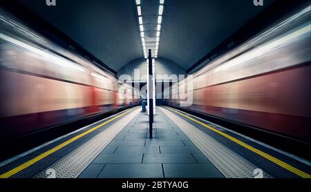 Zwei Züge in Bewegung und ein sitzender Pendler an der Londoner U-Bahn-Station, Clapham Common, Clapham, London, England, Großbritannien, Europa Stockfoto